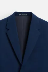 Blazer slim fit azul marino confeccionado en tejido con viscosa. Tiene cuello con solapas de muesca, manga larga con puño con botones, bolsillo de vivo en el pecho, bolsillos de solapa en la cadera, bolsillo interior y aberturas en la espalda.