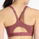 Top deportivo New Balance Essential Run Bra color borgoña, de soporte completo, diseñado para actividades de alto impacto. Confeccionado con tejido de secado rápido NB DRY, relleno incorporado, banda inferior ajustable con cierre de gancho y ojal, y tirantes regulables.