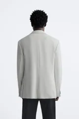 Blazer straight fit color gris claro confeccionado en tejido con viscosa. Tiene cuello con solapas de muesca, manga larga acabada en puño con botón, bolsillo de vivo en pecho, bolsillos de plastrón en cadera y bajo con aberturas en espalda. Cierre frontal de botonadura.