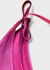 Top de bikini con efecto degradado en tonos rosados y fucsias, con tirantes finos y cierre de lazos laterales.