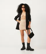 Vestido corto color beige, de canalé con tirantes anchos y recortes con repuxados.