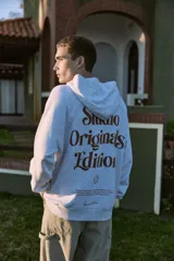 Canguro gris melange con capucha, mangas largas y estampado en la espalda con la inscripción "Studio Originals Edition" en color marrón.