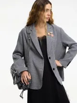 Blazer a cuadros blanco y negro con botones y solapa en la parte delantera. Tiene apliques de pines y bolsillos con solapa.