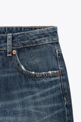 Pantalón de jean celeste claro, de tiro bajo, corte wide leg y largo hasta el tobillo. Tiene cinco bolsillos, cierre frontal con cremallera y botón metálico.