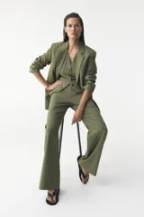 Blazer verde oliva de Zara Woman Collection, con cuello solapa, manga larga, bolsillos de vivo con solapa y cierre frontal con botones.