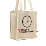 Bolso tipo tote bag de tela color crudo con asas de hombro. Estampado frontal con un reloj y la frase "TODO LOGRO TOMA SU TIEMPO".