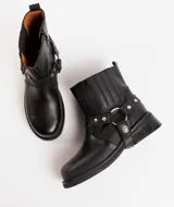 Bota corta negra de cuero vacuno con estribo desmontable, suela de caucho, cierre interno y punta redonda.