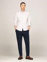 Camisa de algodón Oxford a rayas verticales blancas y beige, de corte regular, con cuello abotonado, mangas largas con puños abotonados y logo de Tommy Hilfiger bordado en el pecho.
