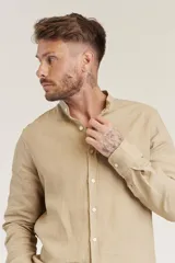 Camisa de lino color beige claro, de corte slim, con cuello mao y mangas largas.