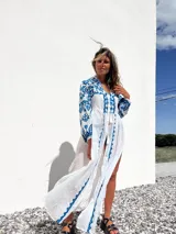 Túnica playera blanca traslúcida con bordados azules, mangas largas y abertura frontal.