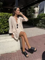 Vestido corto color beige de fibrana, con escote en V, mangas 3/4 con volados y falda con volados.