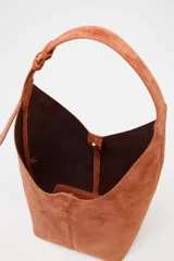 Bolso hobo de gamuza color marrón con asa de hombro ajustable.