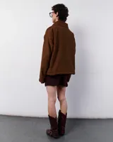 Chaqueta marrón de pana con forro polar, cierre frontal con cremallera y bolsillos laterales. Presenta bordados a mano en forma de zigzag en el frente y los bolsillos.