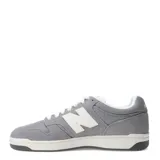 Championes New Balance modelo 480 Lifestyle, color gris con detalles en blanco. Presentan una silueta de corte bajo inspirada en el baloncesto, con capellada de gamuza y malla, y logo "N" blanco en los laterales. La suela es de goma en dos tonos: blanco y gris oscuro.