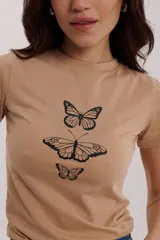 Remera color beige con estampado de mariposas negras en el frente.