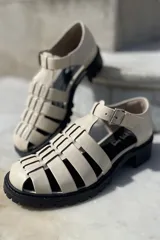 Sandalias de cuero color cobre con diseño de tiras entrecruzadas, hebilla lateral y suela track color negro.