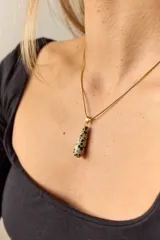 Collar dorado con cadena fina y dije colgante en forma de lágrima de piedra natural azul con vetas blancas.