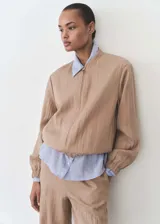 Chaqueta bomber color beige con cierre frontal, cuello mao y puños elásticos.