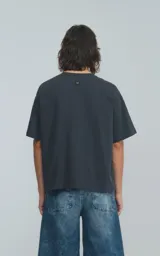 Remera de manga corta color gris oscuro (gris mamba) con calce boxy fit. Presenta un pequeño logo bordado en el pecho.