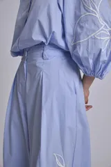 Pantalón palazzo azul marino con bordado de flores blancas en la parte inferior de ambas piernas.
