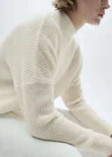 Sweater color crudo de punto medio, cuello perkins y manga larga. Diseño oversize con terminaciones de canalé.