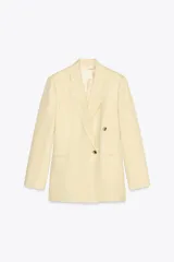 Blazer color crema confeccionado en hilatura con lino, de corte recto, con cuello solapa de muescas y manga larga acabada en abertura y botones. Tiene bolsillos delanteros y cierre frontal cruzado con botones.
