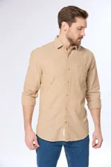 Camisa de lino color beige, de manga larga, con cuello clásico y bolsillo en el pecho.