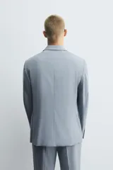 Blazer celeste de corte slim fit, con solapas de muesca, manga larga con botones en los puños, bolsillo de vivo en el pecho, bolsillos de solapa en la cadera, bolsillo interior, aberturas en la espalda y cierre frontal con botones.