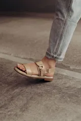 Sandalias bajas doradas de cuero, con dos tiras anchas en el empeine y hebilla lateral ajustable.