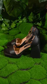 Sandalias negras de cuero sintético, con plataforma y taco cuadrado. Tiras anchas sobre el empeine y pulsera al tobillo con hebilla metálica.