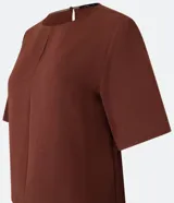 Blusa color ladrillo de mangas cortas confeccionada en crepé texturizado, con cuello redondo y abertura en la espalda. Corte recto y holgado.