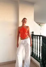 Top corto naranja con lentejuelas, escote halter y espalda descubierta. Se ata con tiras en la espalda y en el cuello.