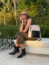 Mochila urbana color gris con detalles en cuero sintético negro. Cuenta con un compartimento principal amplio y un bolsillo frontal con cierre.