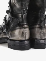 Botas de caña media color gris con efecto desgastado, cierre lateral con cremallera, apliques de tachas metálicas y correa con hebilla.