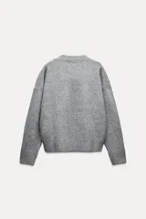 Sweater gris de punto con escote en V y manga larga.
