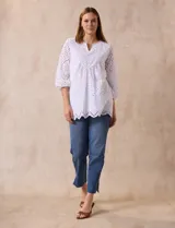 Blusa blanca de algodón con bordado broderie, cuello a la base con escote en V y mangas tres cuartos amplias con puño elastizado.