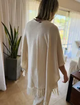 Ruana tejida color arena con flecos.