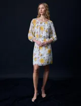 Vestido corto de gasa estampada con flores amarillas, marca Sandra Darren. Tiene escote redondo, mangas 3/4 con puño elastizado y lazo de ajuste en la cintura.