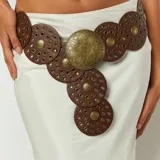 Cinto marrón de cuero sintético con apliques metálicos dorados y hebilla circular grande.