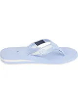 Ojotas de mujer con base celeste claro y suela con detalles de franjas blancas. Tira de tela con diseño geométrico en blanco y celeste, y logo de Tommy Hilfiger impreso en la plantilla.