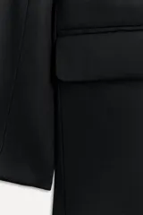 Blazer negra oversize de algodón con cuello solapa con muesca, manga larga con hombreras y hombro caído, bolsillos con solapa en delantero y de vivo en pecho, detalle de solapa en interior, forro interior y cierre frontal con botones.