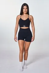 Conjunto deportivo negro compuesto por un top con tiras cruzadas en la espalda y un short ajustado con logo blanco en la cadera.