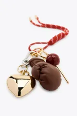Llavero con cordón rojo y charms colgantes: corazón dorado, guante de boxeo marrón y esfera roja.