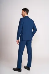 Traje de vestir azul con solapa de satén, compuesto por saco con cierre de un botón, pantalón de corte entallado y moño de satén azul.