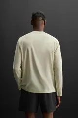 Camiseta deportiva de manga larga color amarillo pálido, confeccionada en tejido técnico perforado, ligero y elástico.