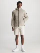 Campera beige con capucha, cierre frontal con cremallera, bolsillos laterales con cremallera y logo de Calvin Klein en la manga.