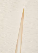 Vestido largo color crema, con escote off-shoulder, mangas largas con puños drapeados y abertura lateral en el ruedo.