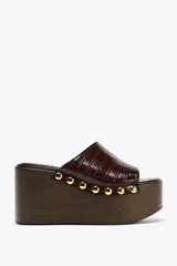 Mules con plataforma de madera y capellada marrón con textura de piel de cocodrilo.