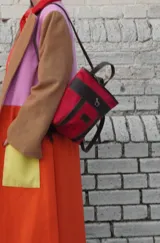 Mochila pequeña color borgoña con detalles en cuero marrón, asa de mano y correas ajustables.