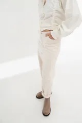 Pantalón color crudo, de corte recto, con bolsillos frontales y traseros, costuras contrastantes y cierre frontal.